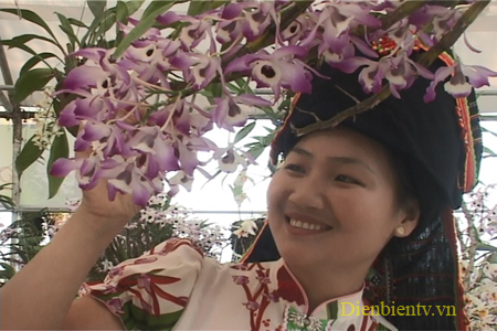 Thiếu nữ Thái e ấp bên hoa trong trang phục của dân tộc.